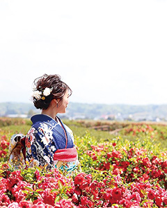 【写真】ボケの花に囲まれた振袖姿の女性