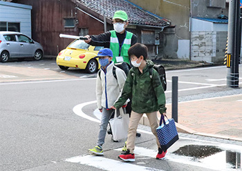 　青パト運転手の阿部幹雄さん(下写真で緑のベスト着用)は、登校時の見守りにも熱心に取り組んでいて、日和山小学校の児童からは「あべちゃん」の愛称で親しまれています