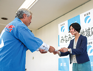 蛭間友里恵さんが渡辺区長から委嘱状を受け取っている写真