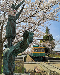 桜の季節の旧月潟駅で角兵衛獅子像と車両の写真