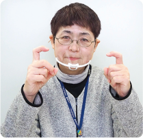 手話通訳者・鈴木さんが顔の前に出している両手の人差し指を内側に曲げている写真