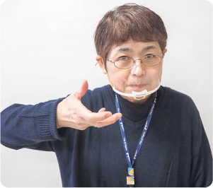 手話通訳者・鈴木さんが軽く開いた右手を前方向に回転させて顔の脇に下した写真