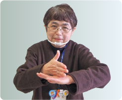 手話通訳者・鈴木さんが胸の高さで片方の手の平を下にし、反対の手を縦に甲の上に乗せている写真