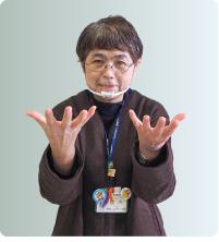 手話通訳者・鈴木さんが胸の前で両手を上向きにパッと開いている写真