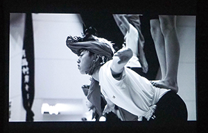 スクリーンにモノクロで映し出された角兵衛獅子の練習をする子供の写真