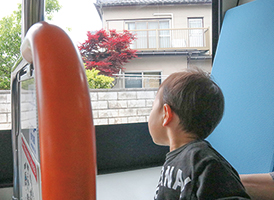 バスから窓の外を眺めている男の子の写真