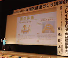 講師の高橋良太さんがステージ上でスクリーンに映し出された画像について説明している写真