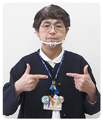 手話通訳者・鈴木さんが胸の前で両手の親指と人差し指でL字を作り、人差し指を中心に向けている写真