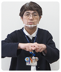 手話通訳者・鈴木さんが両手をチョキにして片方のチョキにもう片方に乗せている写真