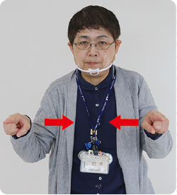 手話通訳者・鈴木さんが胸の高さで両手の人差し指を左右に広げている写真