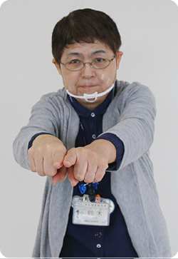 手話通訳者・鈴木さんが胸の前でくっ付けた左右の指を前に出している写真