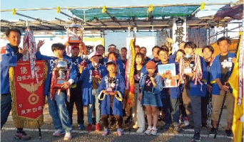 優勝した桜蝶組の人たちが優勝旗とトロフィーをもって記念写真を撮っている写真