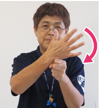 手話通訳者・鈴木さんが「パー」に開いた手をもう片方の「グー」にした手に乗せている写真

