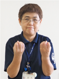 手話通訳者・鈴木さんが両手を「グー」にして上に向けている写真