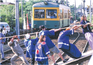 白根大凧合戦西側、廃線前の新潟交通電車線の線路を横断しながら網を引く人々の写真