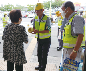 新潟南区交通安全協会のメンバー2人がイオン白根店出入口で啓発品を配布している写真