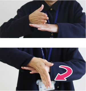手話通訳者・鈴木さんが片方の手の甲に縦にした反対の手を乗せて、前方に倒している写真