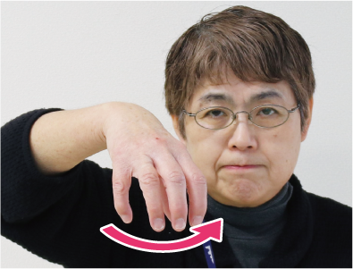 手話通訳者・鈴木さんが顔の前で蛇口をひねるように左右に手を動かしている写真