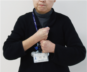 手話通訳者・鈴木さんが両手をグーにして胸の前で縦に重ねている写真