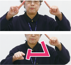 手話通訳者・鈴木さんが両手の人差し指で「ハ」の字を作り、片方の人差し指で「ム」を描いている写真