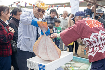 新川漁港で獲れた活ヒラメを手にする漁師