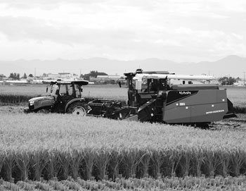 写真　自動運転コンバインおよび自動運転トラクタの連携による稲刈り同時耕運の様子