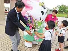 【写真】夏目区長とさつきちゃんにお花を贈呈する園児たち