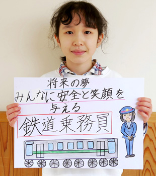【写真】将来の夢みんなに安全と笑顔を与える鉄道乗務員という画用紙を持った子供