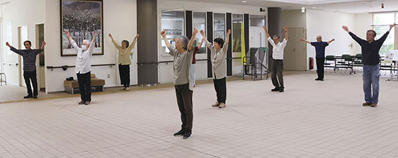 屋内でラジオ体操をしている区民の皆さんの写真