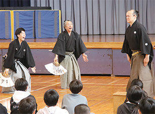 児童が狂言の指導を受ける様子を撮った写真