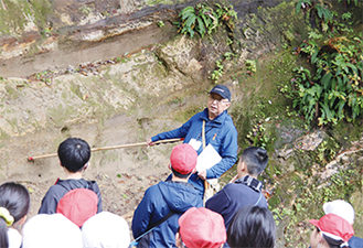 地層の解説を聞く児童たちの様子を撮った写真