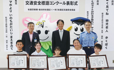 表彰状を授与された児童5人と、（後列右から）秋葉警察署 署長、一般財団法人秋葉区交通安全協会 会長、秋葉区 区長の集合写真