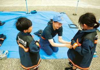 子供たちに消防団の服装を着せている様子