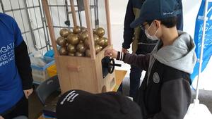 オリジナルの木製ガチャを回す子どもの写真