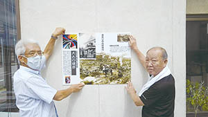 二人でサインを張り付ける場所にサイン案を掲示している写真