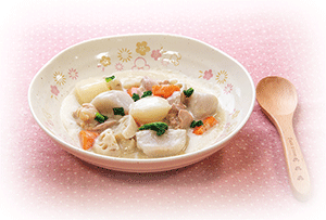 鶏肉と根菜のシチューが盛られたお皿と木製スプーンの写真