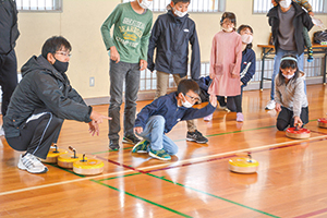 小学生の男の子が黄色いフロッカーを投げ、それをみんなが見守っている写真