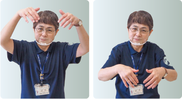 手話通訳者・鈴木さんが頭の高さまで挙げた両手の指を下に向けている写真