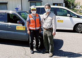 青パトの車両の前に立つ猪股忠雄さんと鈴木弘行さんの写真