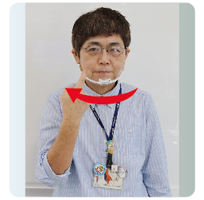 手話通訳・鈴木さんがその人差し指を口の右端に動かしている写真