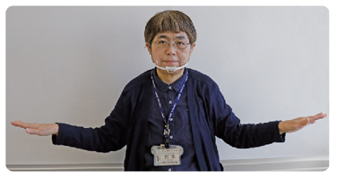 手話通訳者・鈴木さんがその両手を胸の高さまで下ろしている写真