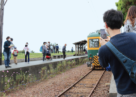 男性がスマートフォンでかぼちゃ電車を撮っている写真