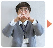 手話通訳者・鈴木さんが左右の人差し指を顔の前でクロスしている写真