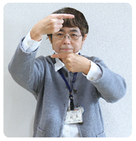 手話通訳・鈴木さんがその人差し指を顔の前に持ってきて、横に平行にしている写真