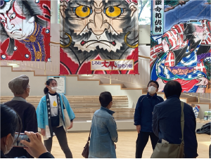 白根大凧と歴史の館で前田さんがに立って説明しいる写真