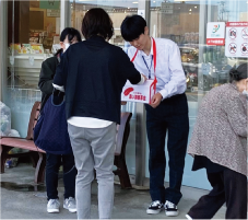 商業施設の出入り口で募金箱を持ち、募金を呼び掛ける男子生徒の写真