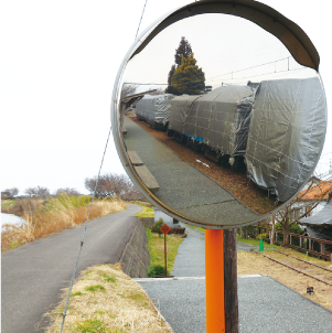 冬囲いをしたかぼちゃ電車が写り込んだカーブミラーの写真