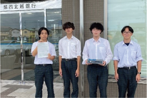 第四銀行白根支店前で募金領収書を手にした白根高校男子生徒4人の集合写真
