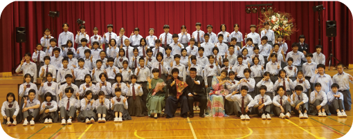 篠笛奏者・狩野泰一さんを再現列中心にして６列になった生徒の集合写真