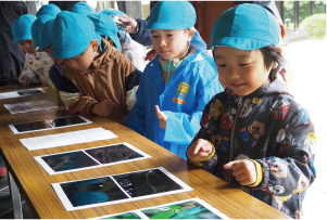 園児がホタルの写真を見ている写真